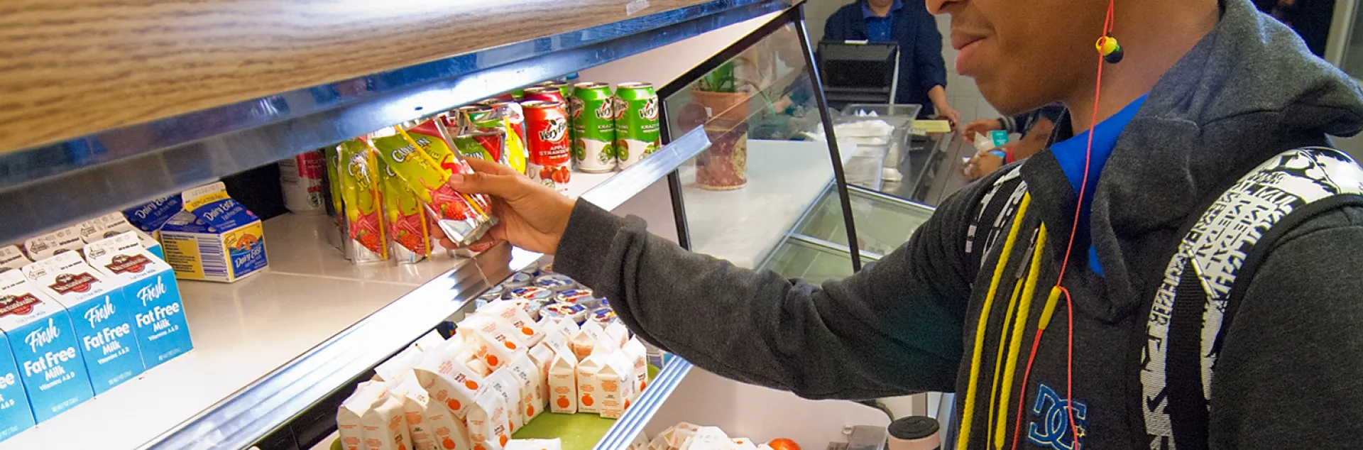 A high school student grabs a pre-made meal from the school cafeteria lunch line.
