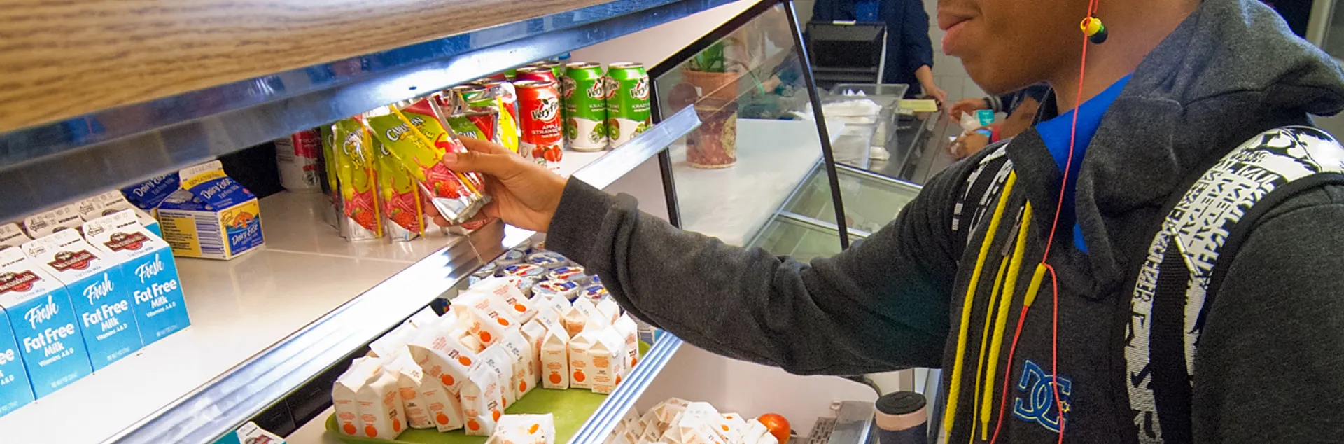 A high school student grabs a pre-made meal from the school cafeteria lunch line.