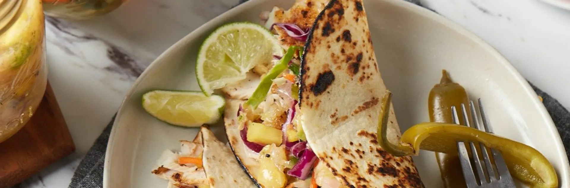 two jalapeno tacos on a plate with a fork full of jalapenos and lime wedges
