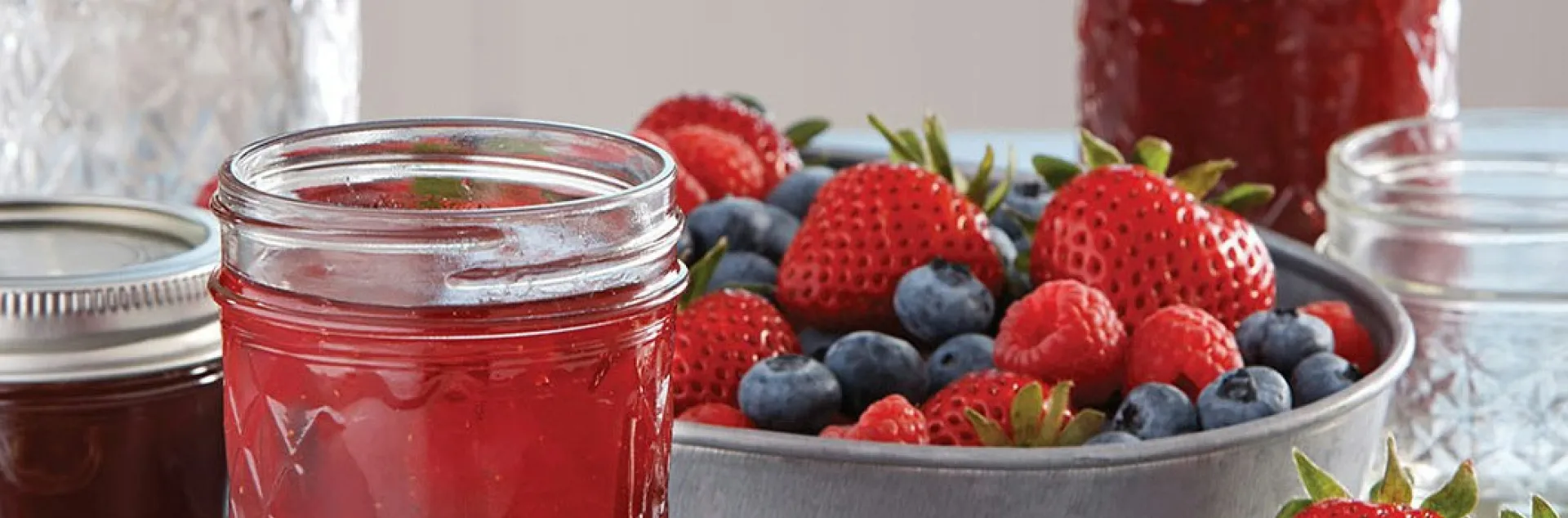 jar of berry jam with bowl of berries next to it