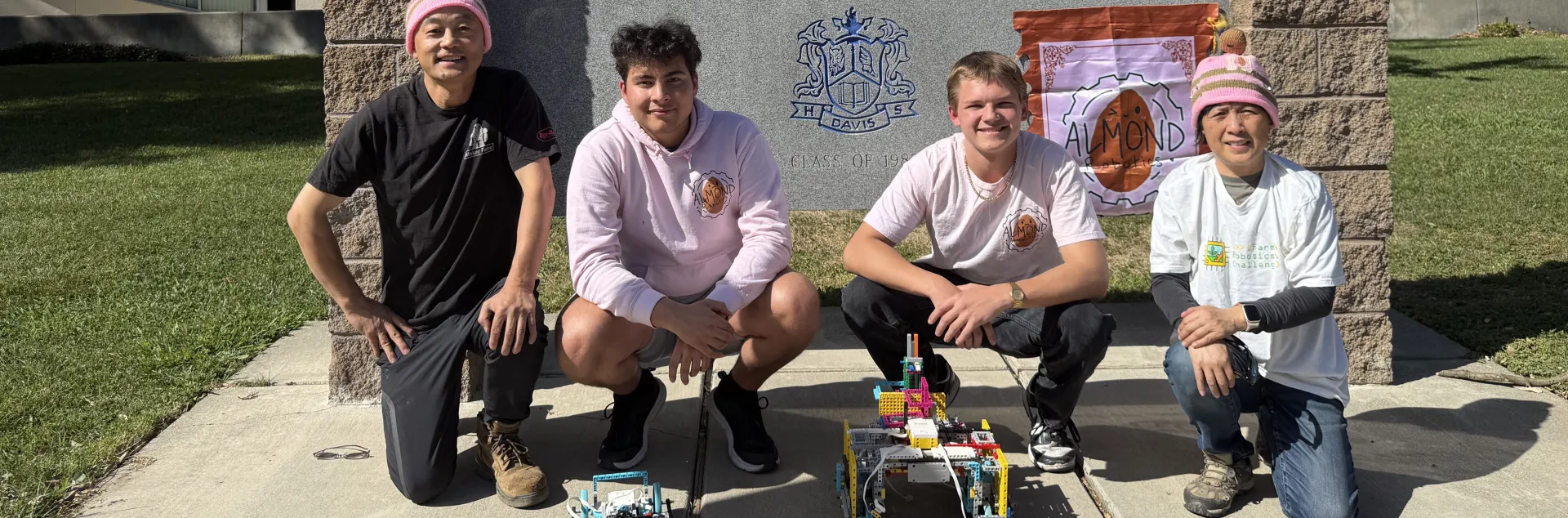 Almond Robotics, Modular Learning, Inc. team crouch by the Davis Senior High School sign