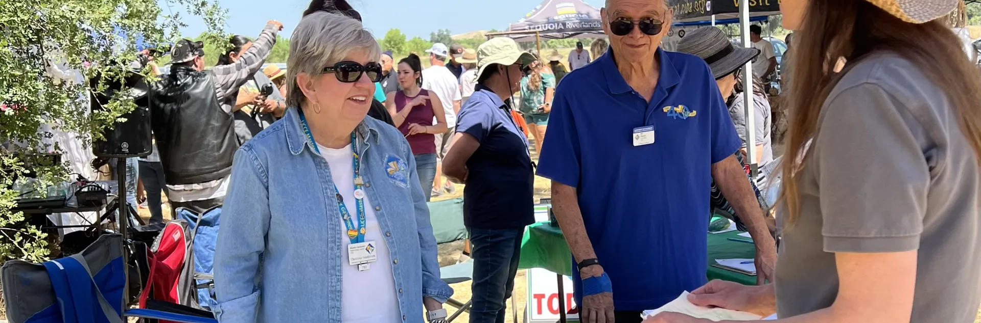 2 master gardeners helping an adult at the Go Native booth