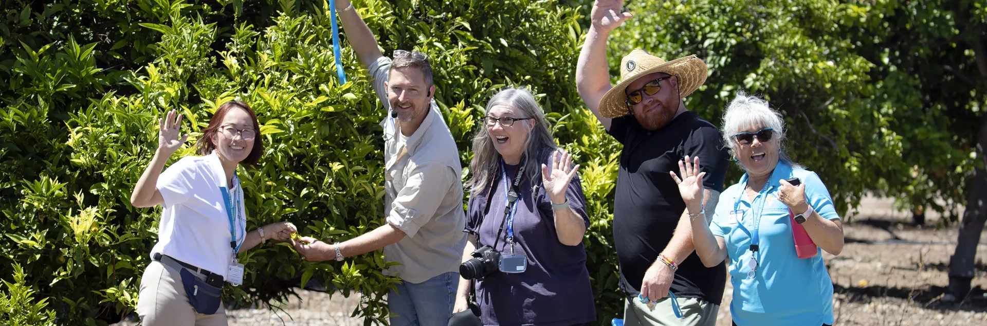 Master Gardeners waving at camera in orchard