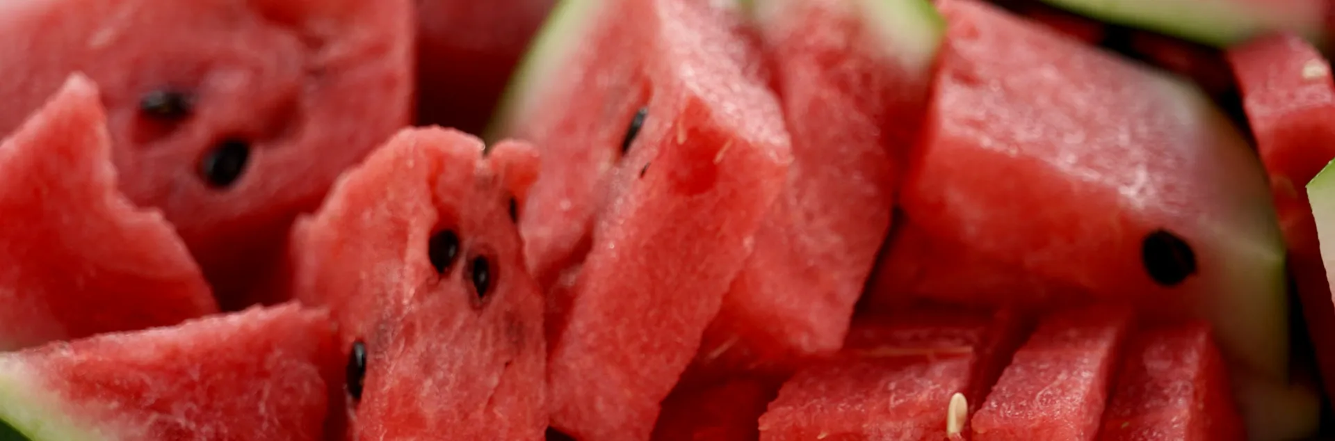 red watermelon with seeds cut into triangles with rinds on