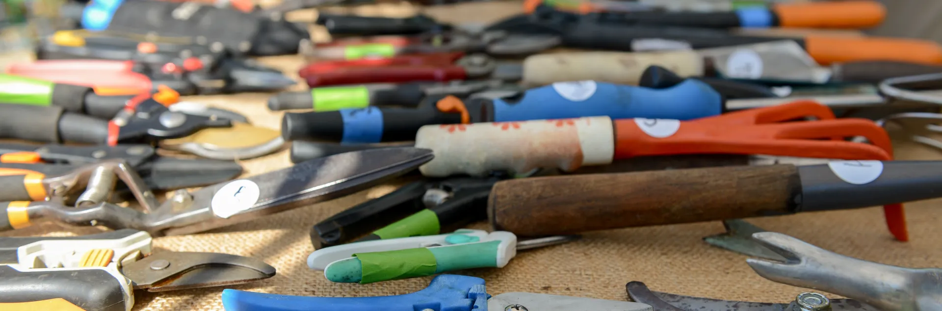 Closeup of many colorful gardening hand tools on a table.
