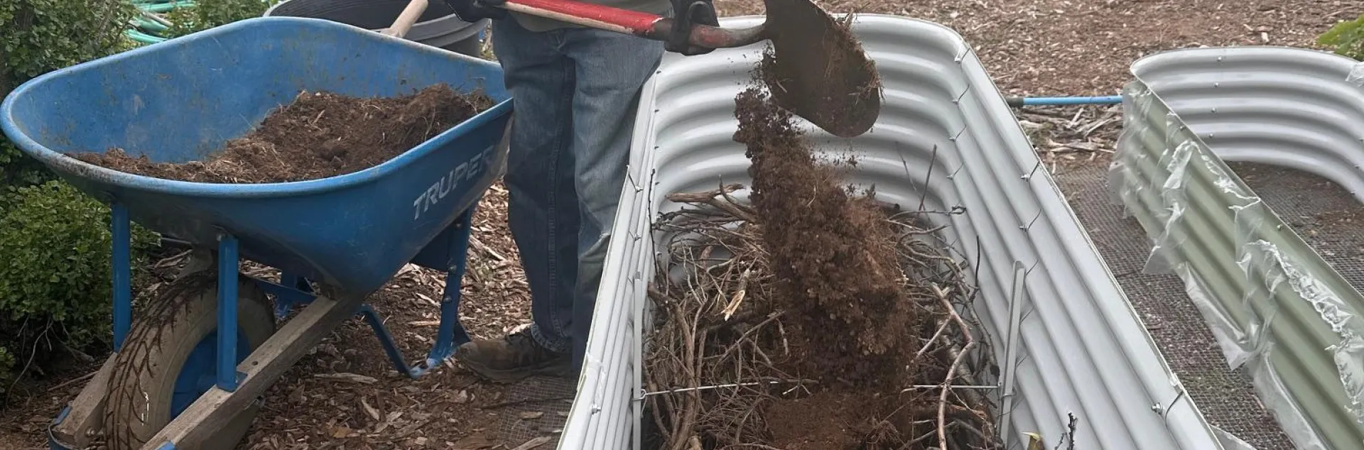filling raised bed with sticks on the bottom and soil on top