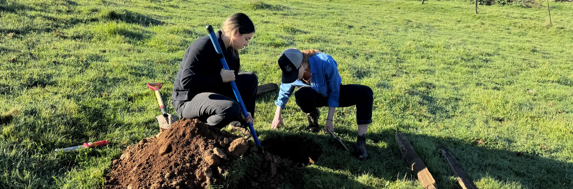 Two people looking at soil pit in rangeland