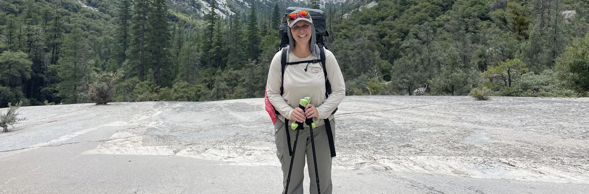 Kristin Polidoro stands with hiking poles, with Kings Canyon behind her and the South Fork of the Kings River below, unseen