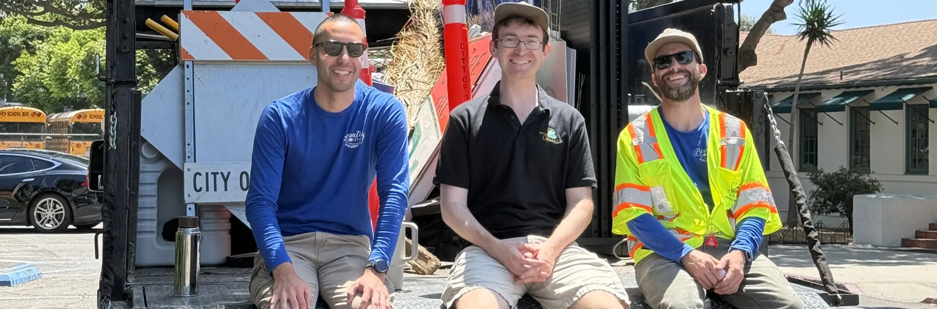 Jason Scott-Sheets, middle, sits with two Public Works colleagues at the back of a truck filled with tools and signs during a community cleanup event
