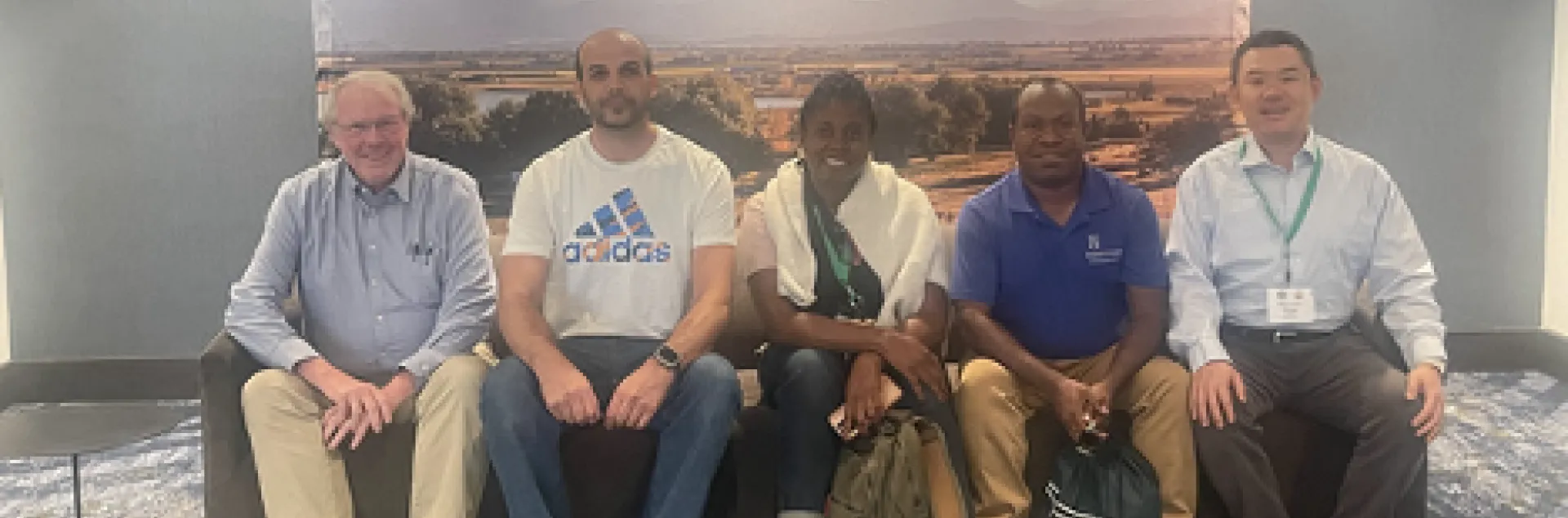 Five people sit on a bench in front of a Colorado State University banner