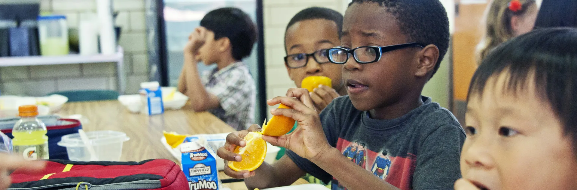 Several elementary-aged students eating at a table during lunch time. 