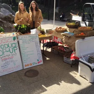 Margaret Bishop (right) and Arianna Khieninson (left) stand behind a table of fresh foods for sale