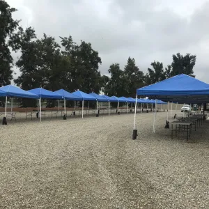 a gravel parking lot with blue tents set up for an event