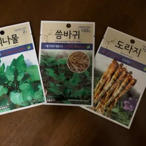 three packages of seeds with writing in Korean on them