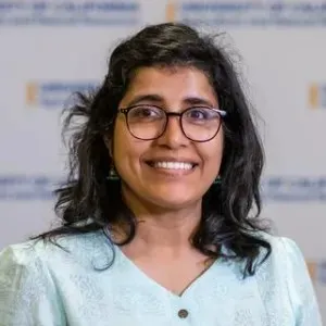 a woman with black hair and glasses wearing a light blue top