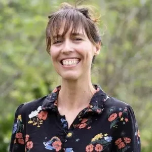 A woman with brown hair and bangs wearing a black floral top