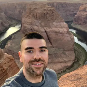 A man with black hair standing in front of Horseshoe Bend in Arizona