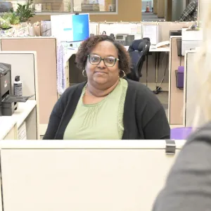 Woman sitting at a desk with a green shirt on