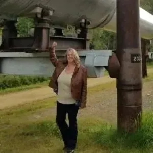 woman with blonde hair wearing a brown leather jacket in an outdoor setting