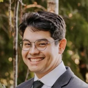Smiling man with short brown hair wearing a suit and tie.