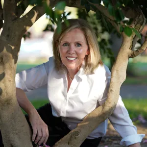 Smiling woman with blond hair and a white shirt.