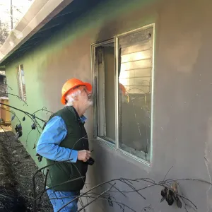 A picture of a man assessing post-fire damage on a structure.