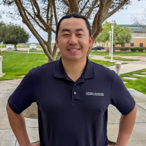 man with UCANR polo shirt outside with tree behind