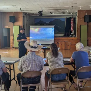 A CAL FIRE employee presenting on a projector screen to a group of landowners that are seated in front of him.