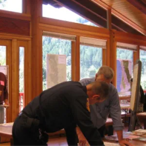 A community member and a fire personnel member leaning over a map on a table together.