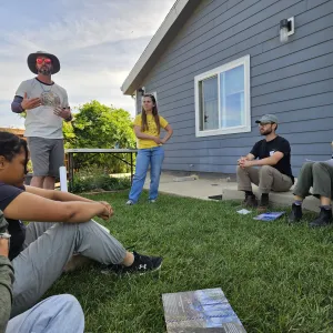 Tree School participants sit outside for a home hardening presentation.