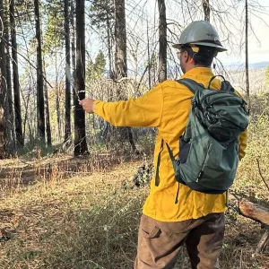 A person monitoring weather conditions during a prescribed burn. They are swinging a sling psychrometer.