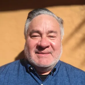A smiling Master Gardener in a blue shirt against an orange background.