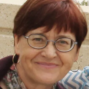 A smiling Master Gardener in a dark blue shirt wearing glasses and a scarf.