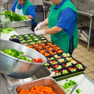 School food service staff prepare healthy meals in a school kitchen.