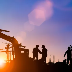 Silhouette of construction workers with hardhats at worksite