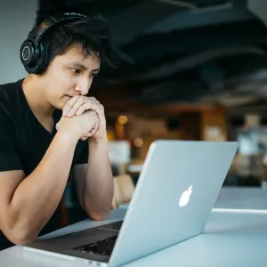 A student is looking at a computer while sitting at a desk.