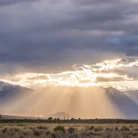 Light rays shining through clouds with mountains in background.