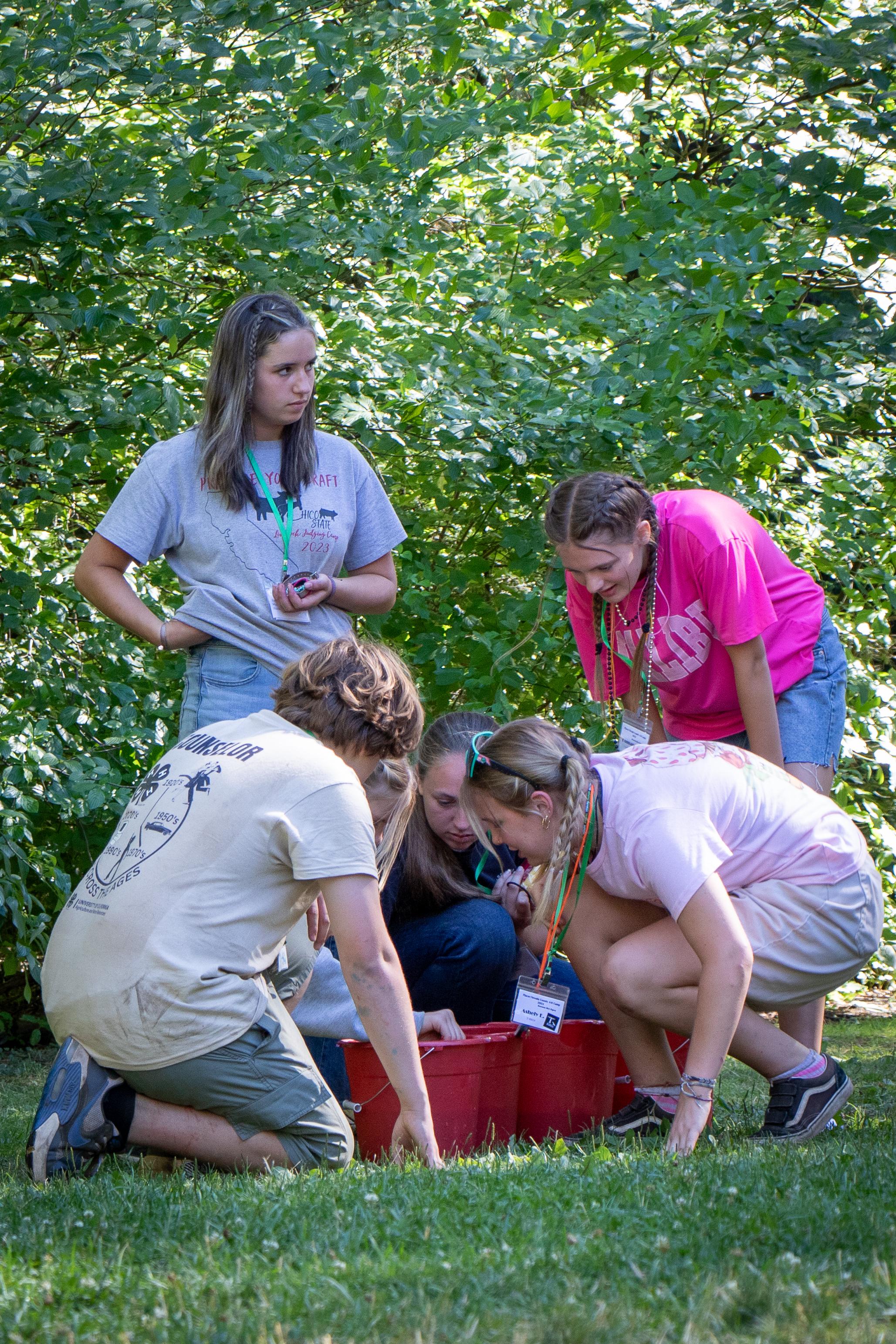 Youth checking water levels in buckets during Meadow Games